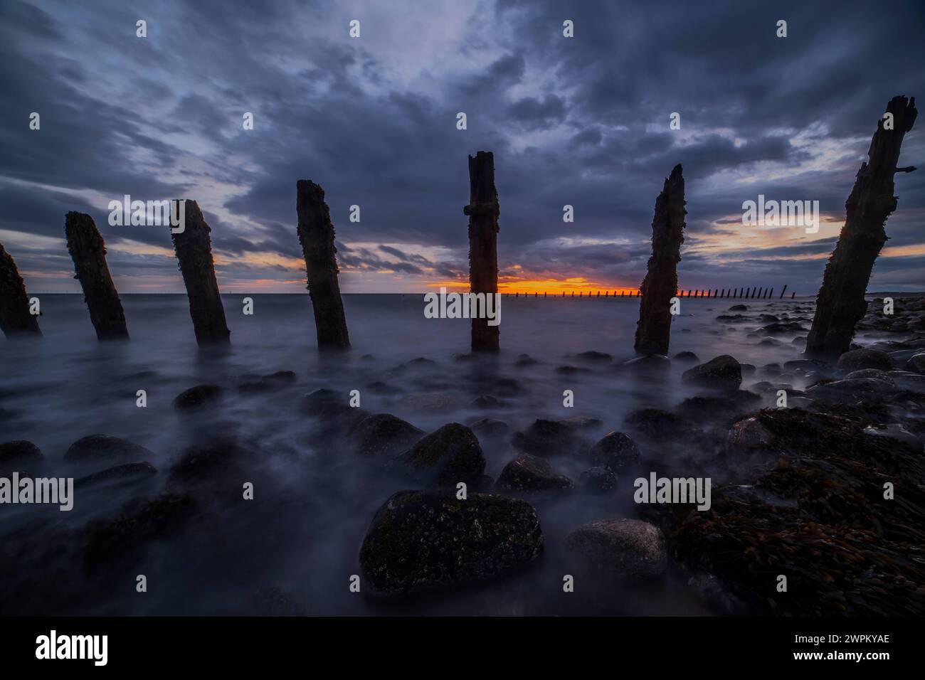 Nuvole di tempesta si riuniscono sul Mare d'Irlanda, indossando difese marittime da South Walney al tramonto dalla costa della Cumbria, Cumbria, Inghilterra, Regno Unito, Europ Foto Stock