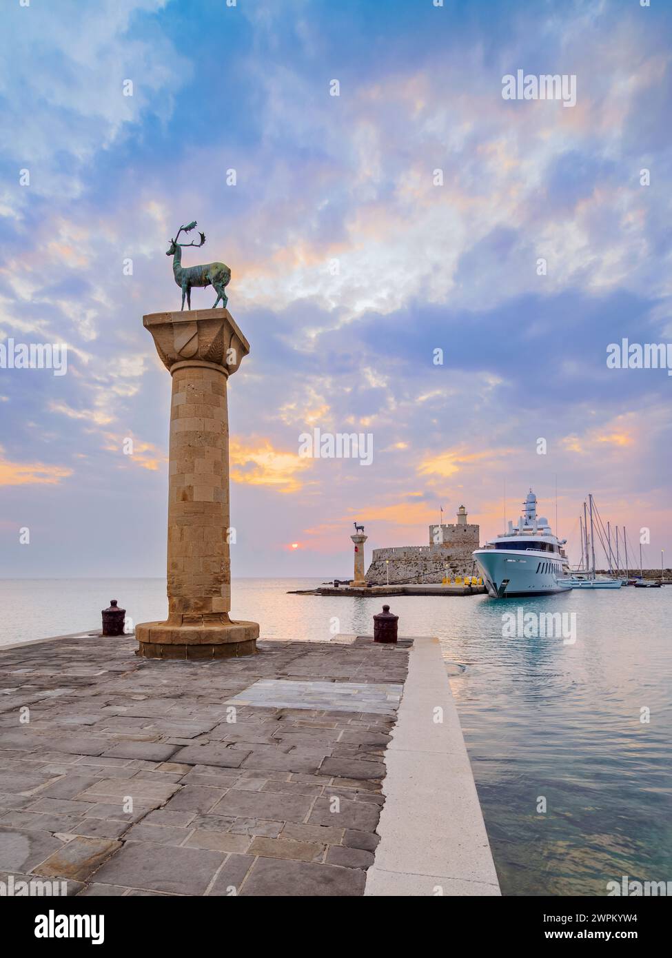 Cervi e cervi sulle colonne all'ingresso del Porto di Mandraki, ex sede del Colosseo di Rodi, la Fortezza di San Nicola sullo sfondo Foto Stock