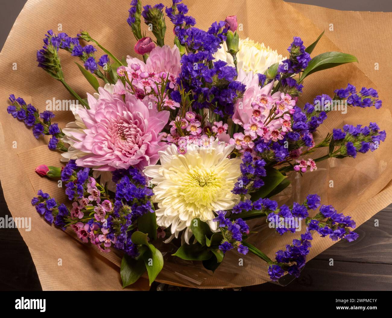 Vista dall'alto di un bouquet di fiori rosa e viola avvolti in carta marrone. Foto Stock