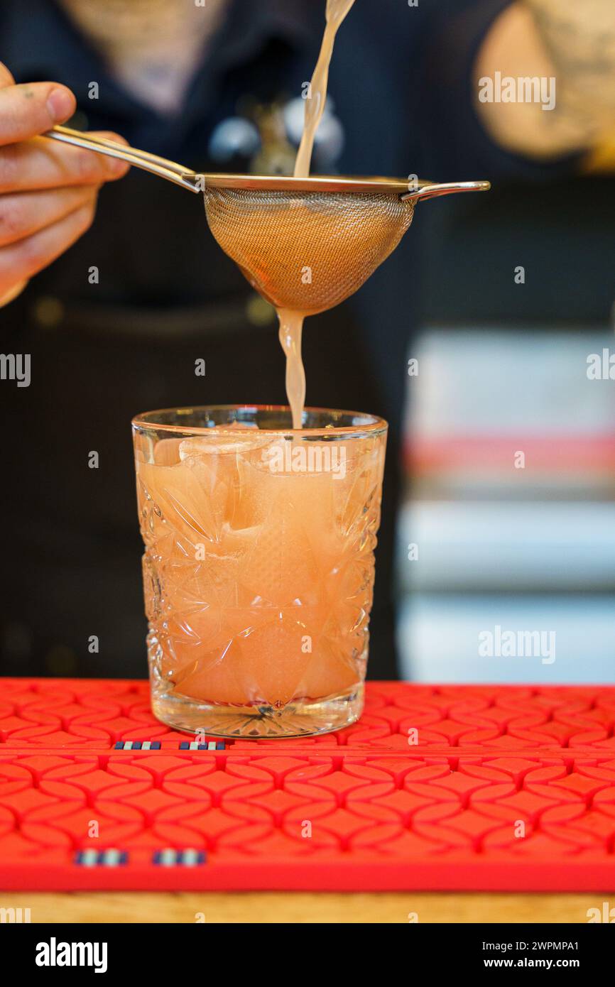 Barman che prepara un cocktail e versa una bevanda in un bicchiere Foto Stock