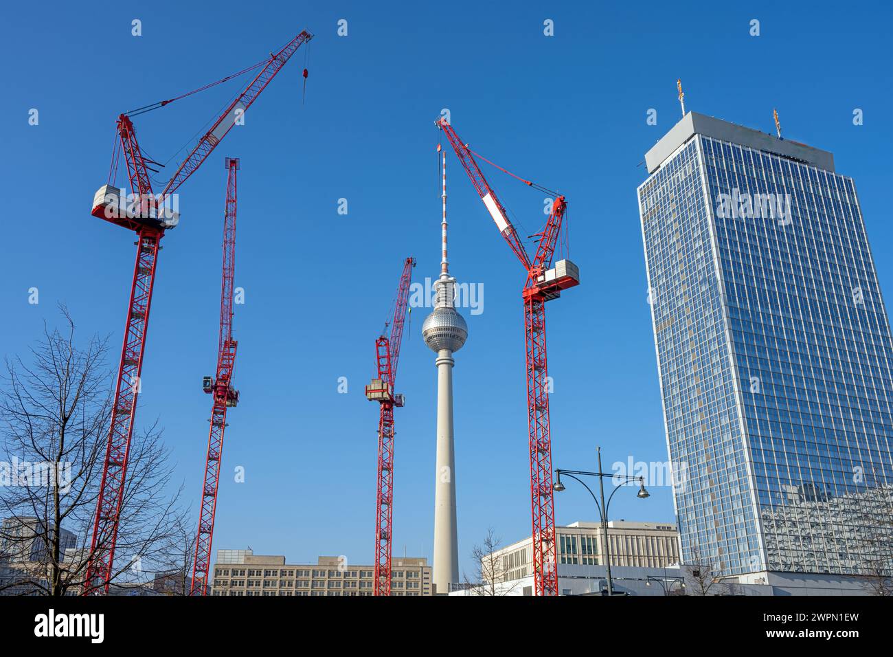 La famosa torre della televisione di Berlino, un grattacielo e quattro gru a torre rosse Foto Stock