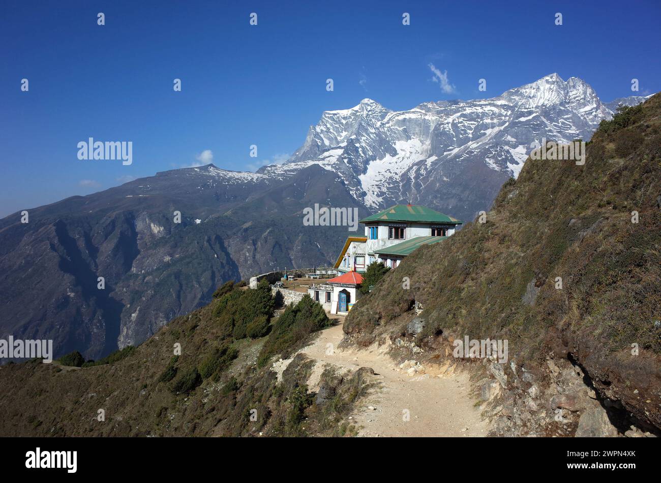 Paesaggio montano dell'Himalaya con sentiero per la pensione nascosto a metà dietro la verde collina e vista del monte Kongde Foto Stock