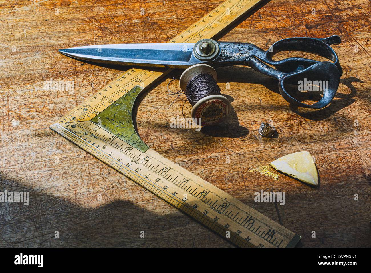 Vecchio strumento di misurazione su misura con forbici e gesso sul banco di lavoro dei sarti Foto Stock