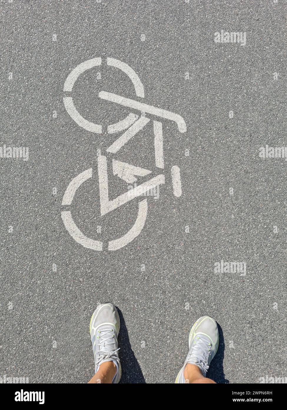 Gambe da donna con scarpe sportive bianche davanti al pittogramma della bicicletta su una pista ciclabile in Germania Foto Stock