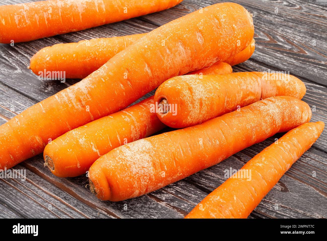 le carote si accumulano su sfondo di legno Foto Stock