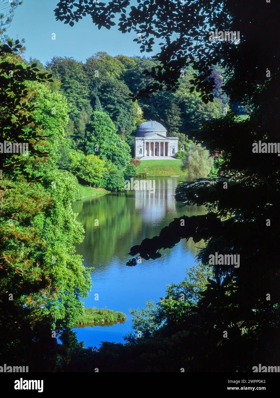 Ammira la vista tra gli alberi del lago e del Pantheon nei giardini paesaggistici di Stourhead, Wiltshire, Inghilterra, Regno Unito Foto Stock