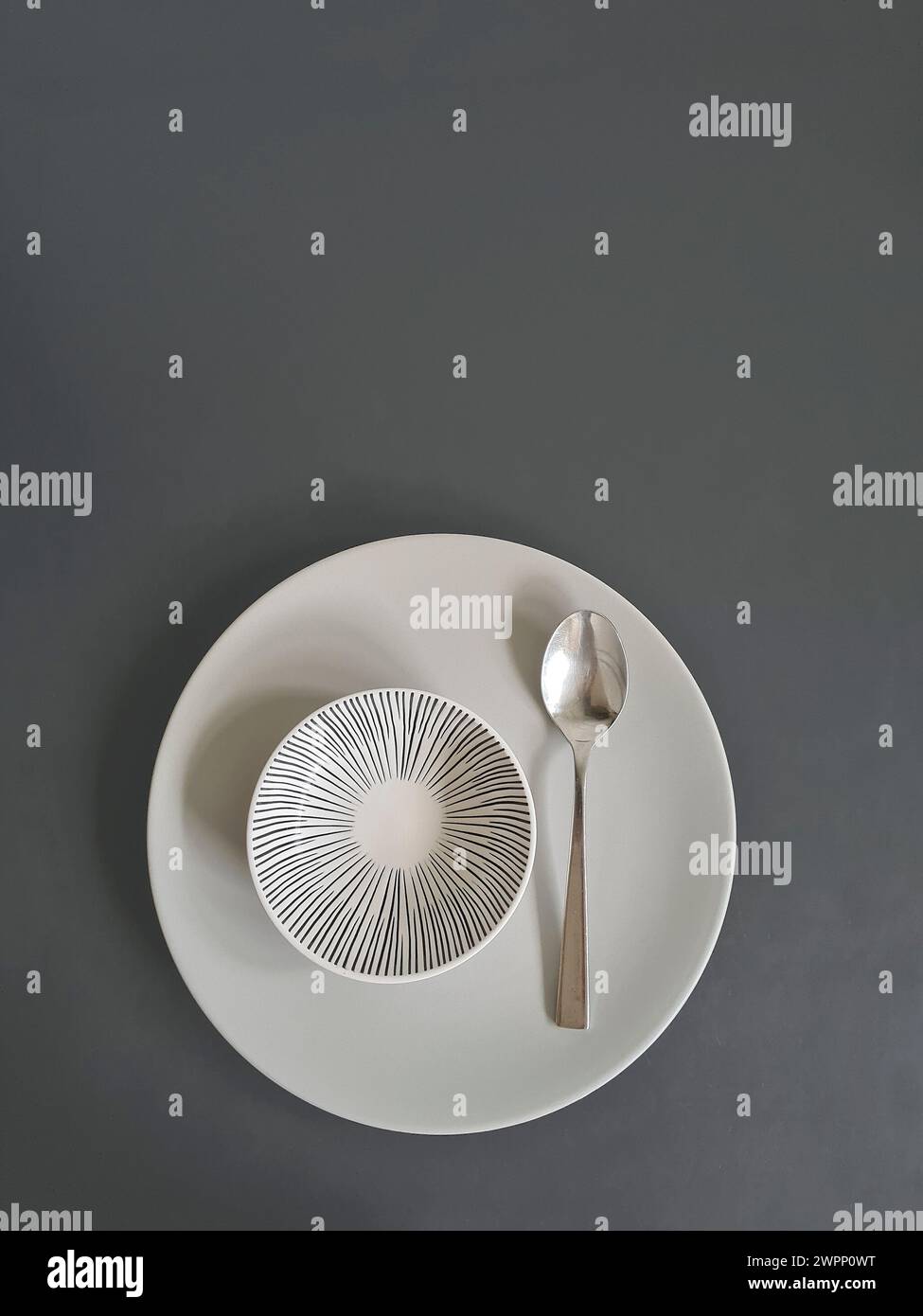 Piatto bianco con ciotola bianca e cucchiaio, minimalista, astratto Foto Stock