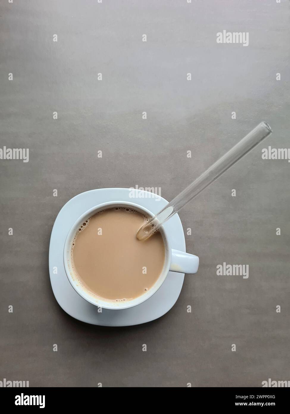 Latte in una tazza bianca con cannuccia di vetro Foto Stock