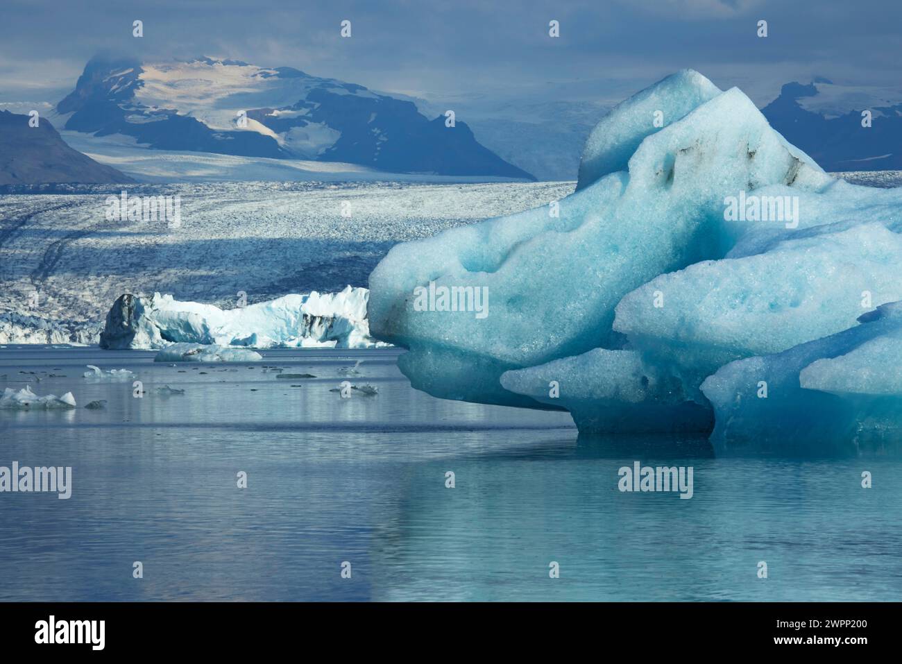 Scintillanti iceberg turchesi sul lago glaciale Joekulsarlon di fronte alle montagne Esjufjell. Foto Stock