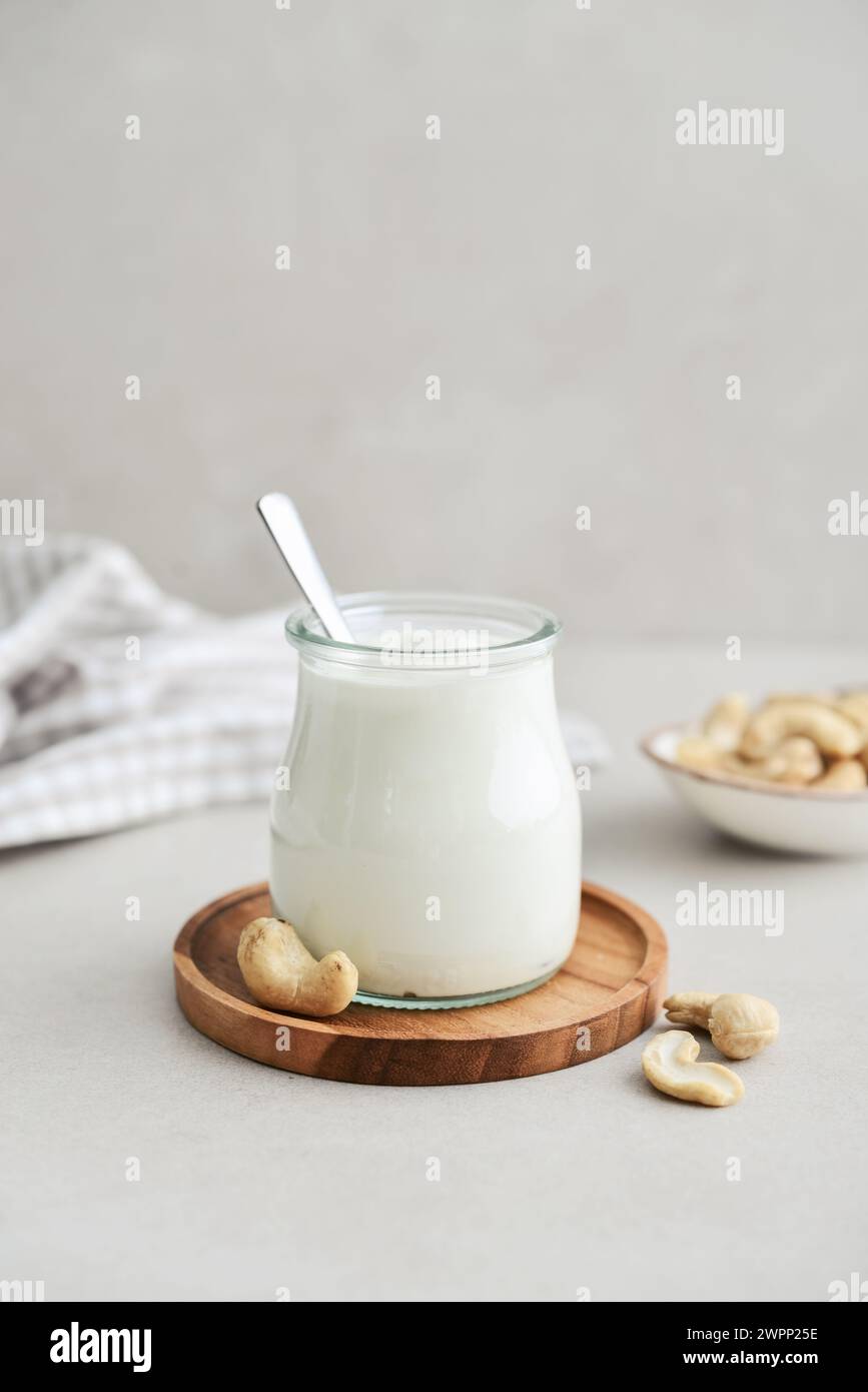 Panna acida anacardi in vaso di vetro con noci su sfondo chiaro, primo piano Foto Stock