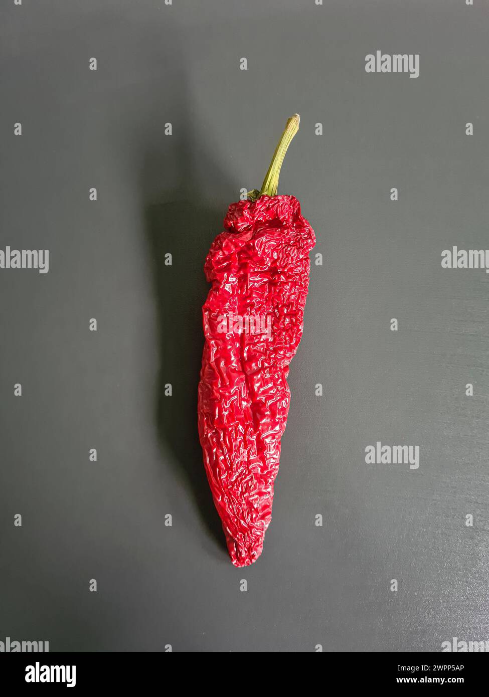 Peperoncino rosso essiccato, un peperoncino su fondo grigio Foto Stock