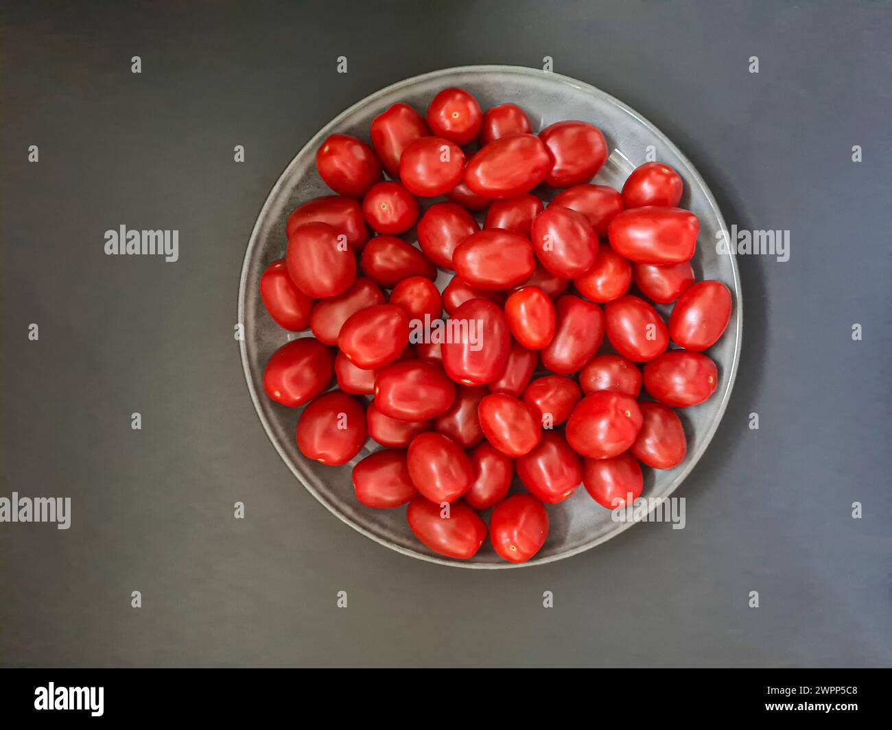 Un piatto di pomodori rossi interi freschi alla luce del giorno Foto Stock