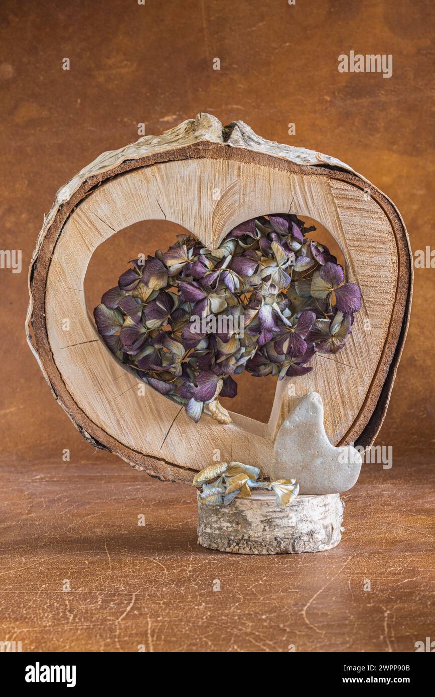 Natura morta floreale di ortensie secche in fiore, flotsam e jetsam, disco di legno con cuore Foto Stock