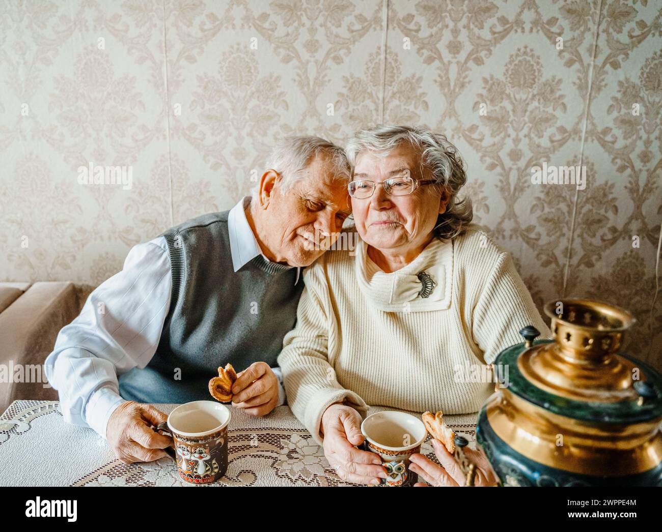 Anziani anziani anziani coppia d'amore romantico bevendo tè con biscotti di samovar. Vecchio pensionato donna insieme. Moglie di un marito anziano in una casa accogliente. Sbirciatina anziana Foto Stock
