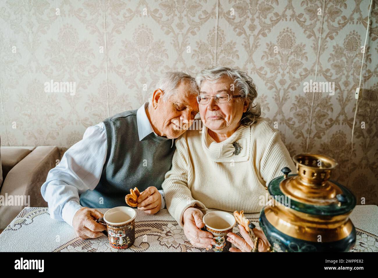 Anziani anziani anziani coppia d'amore romantico bevendo tè con biscotti di samovar. Vecchio pensionato donna insieme. Moglie di un marito anziano in una casa accogliente. Sbirciatina anziana Foto Stock