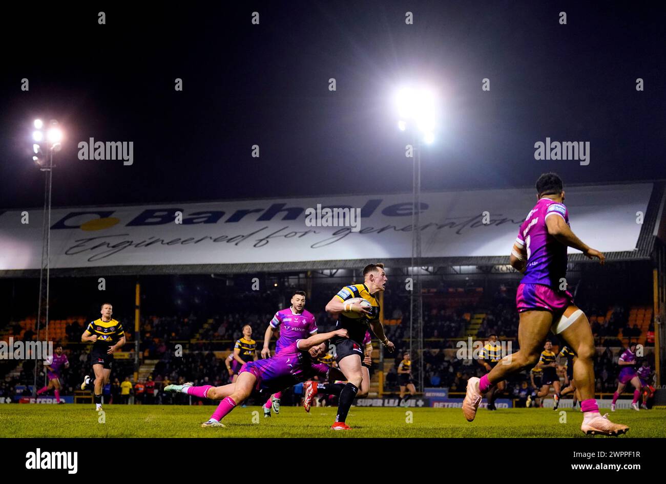 Jack Broadbent dei Castleford Tigers fu placcato da Oliver Rusell degli Huddersfield Giants durante il Betfred Super League match al MEN-A-Hose Jungle di Castleford. Data foto: Venerdì 8 marzo 2024. Foto Stock