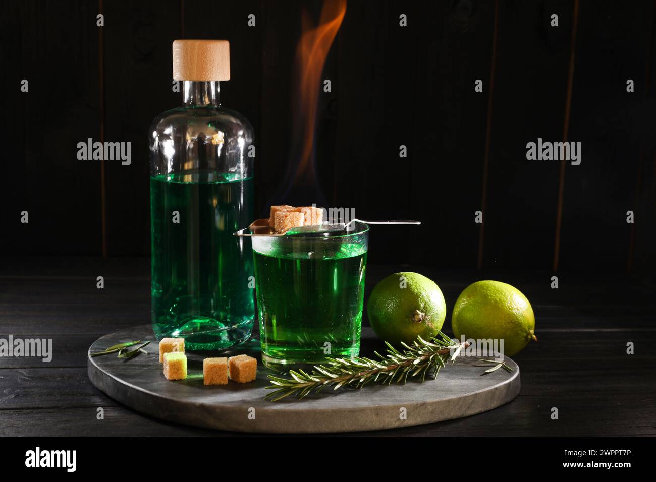 Absinthe in vetro, zucchero di canna fumante, rosmarino e calce su un tavolo di legno. Bevanda alcolica Foto Stock