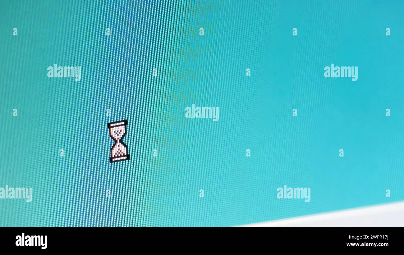 Primo piano di un monitor di computer d'epoca che visualizza l'interfaccia utente di Windows 95 o 98, con il simbolo del cursore a clessidra in attesa. Nosta Foto Stock