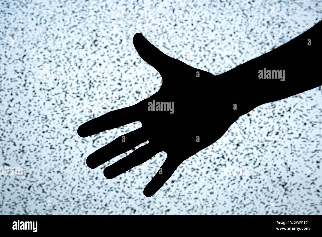 Silhouette scura a contrasto elevato di una mano tesa su uno schermo TV bianco luminoso rumore di fondo, concetto spaventoso spaventoso e minacce digitali Foto Stock