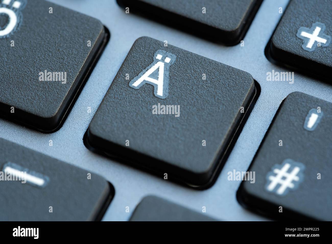 Una macro shot che mostra il Ä con il tasto dieresi su una tastiera nera del computer, con i tasti circostanti leggermente sfocati, dettagli estremamente ravvicinati, no Foto Stock