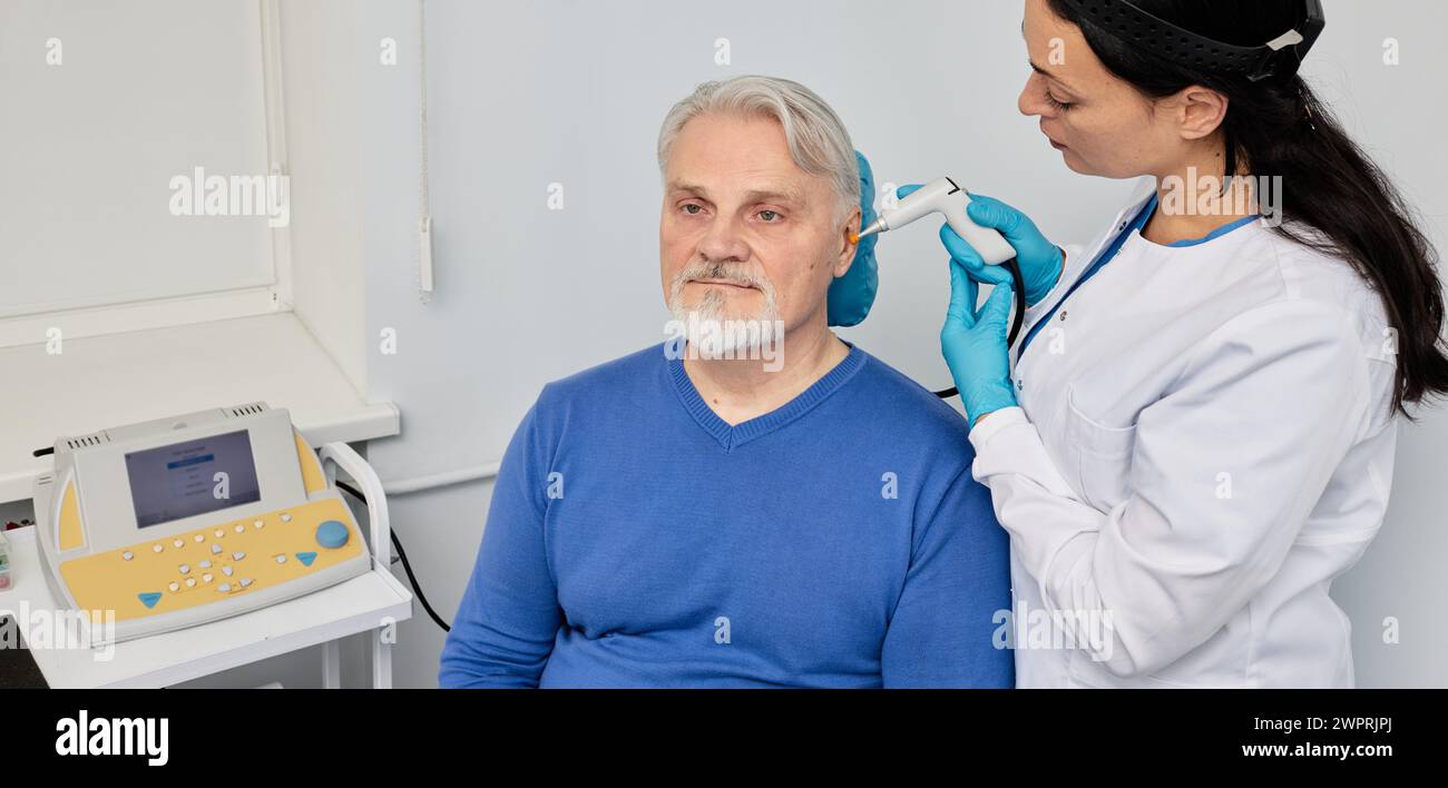 Uomo anziano durante la timpanometria o l'audiometria di impedenza e test della funzionalità dell'orecchio medio con medico ORL che utilizza la sonda timpanometrica presso il centro uditivo Foto Stock