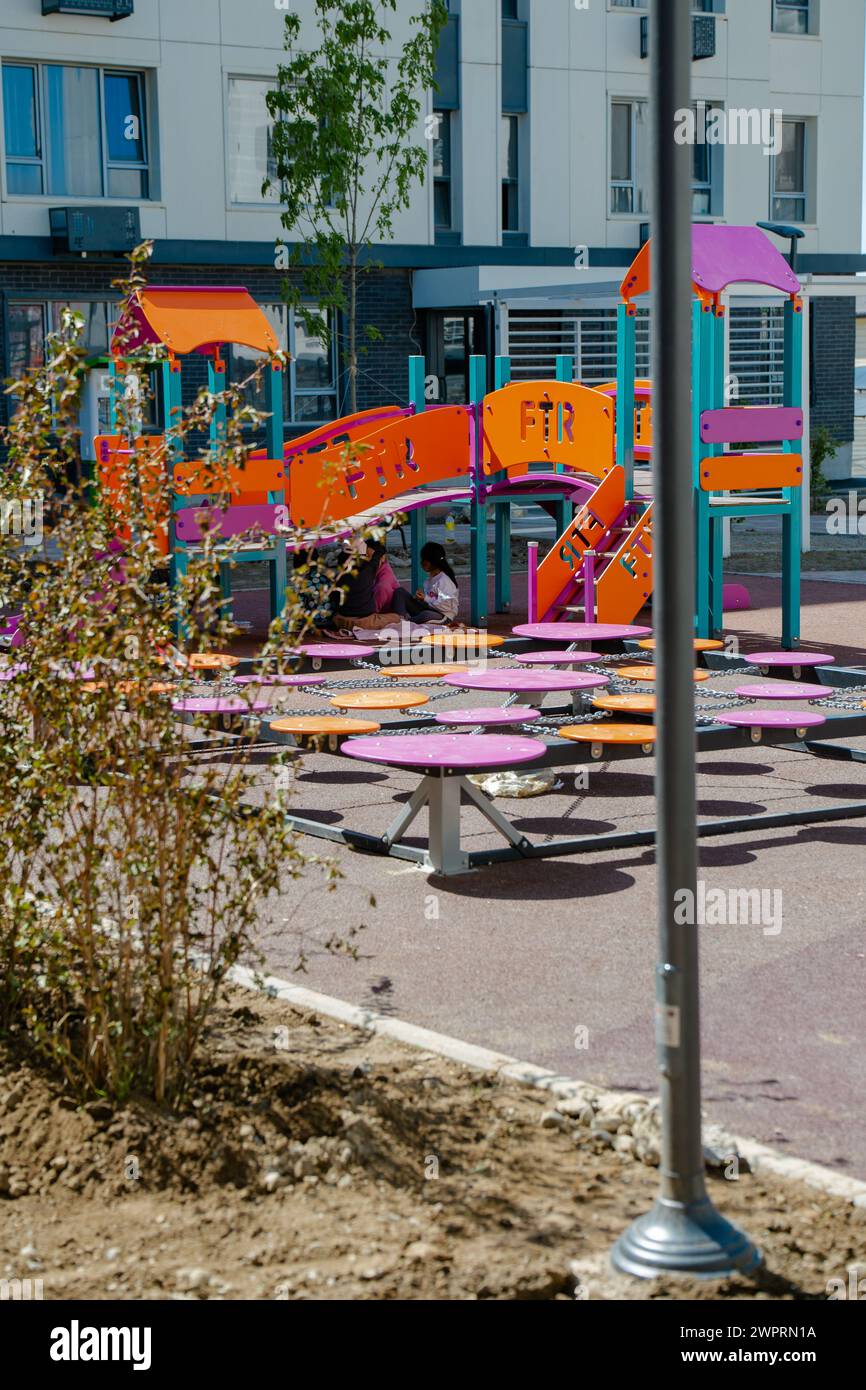 Un vivace parco giochi con attrezzature colorate per i bambini, che crea un ambiente divertente e sicuro per le famiglie da divertirsi insieme. Foto Stock