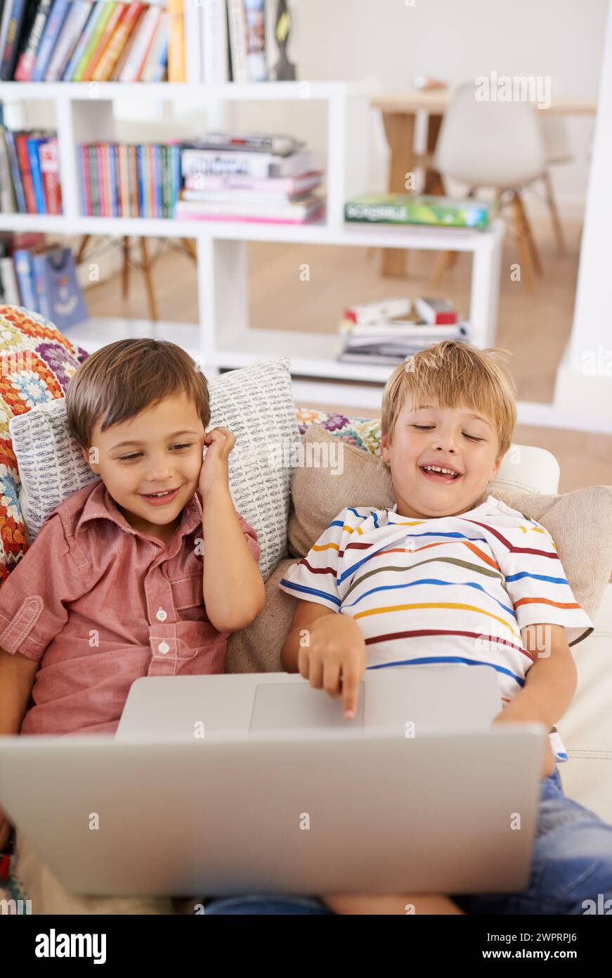 Computer portatile, bambini e fratelli su un divano con cartoni animati, film o film in streaming a casa. Computer, apprendimento o ragazzi in una casa per google IT, ricerca Foto Stock