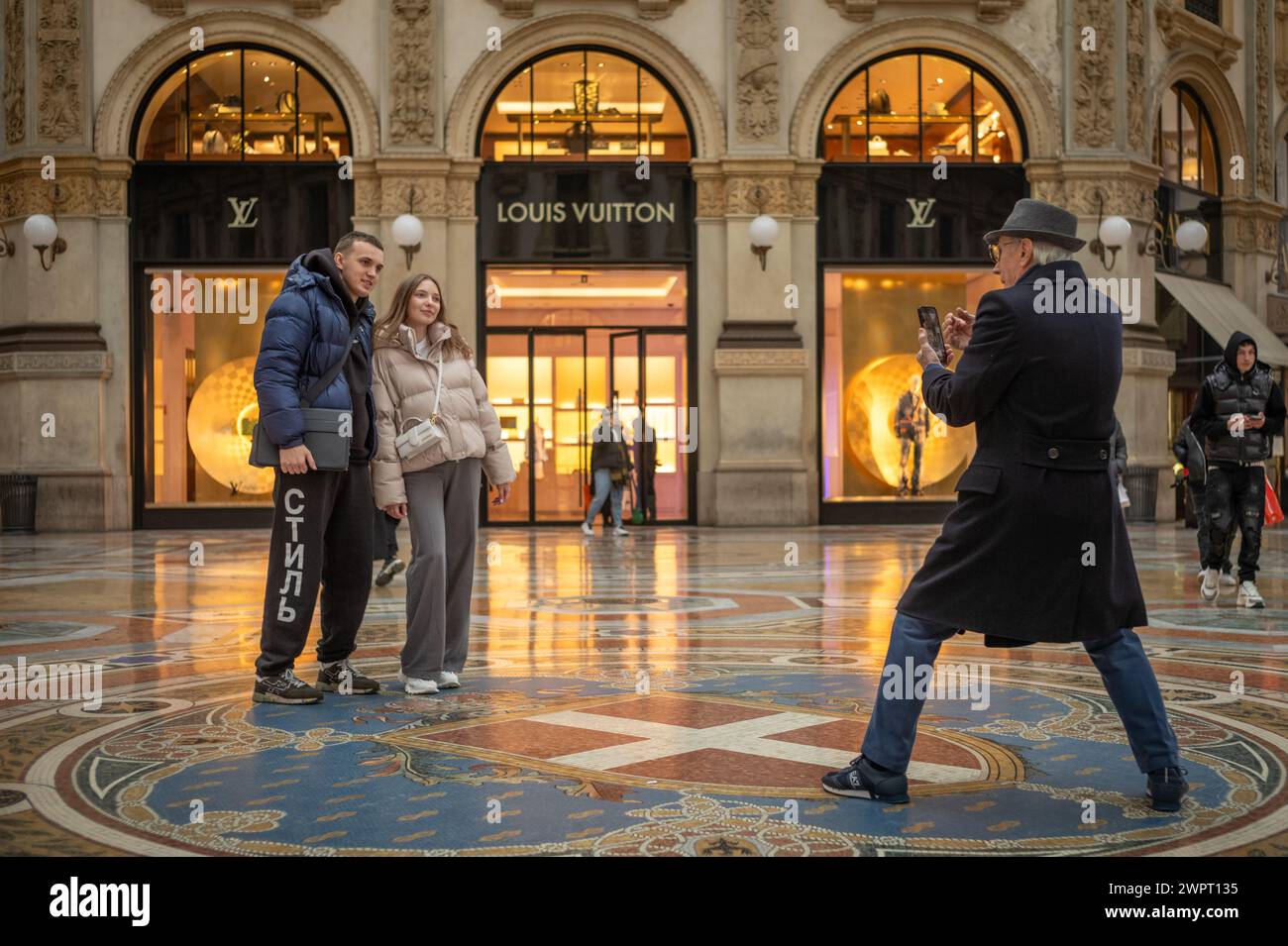 Un paio di posa per una foto fuori dal negozio di stilisti Louis Vuitton all'interno della Galleria Vittorio Emanuele II a Milano, Italia. Foto Stock