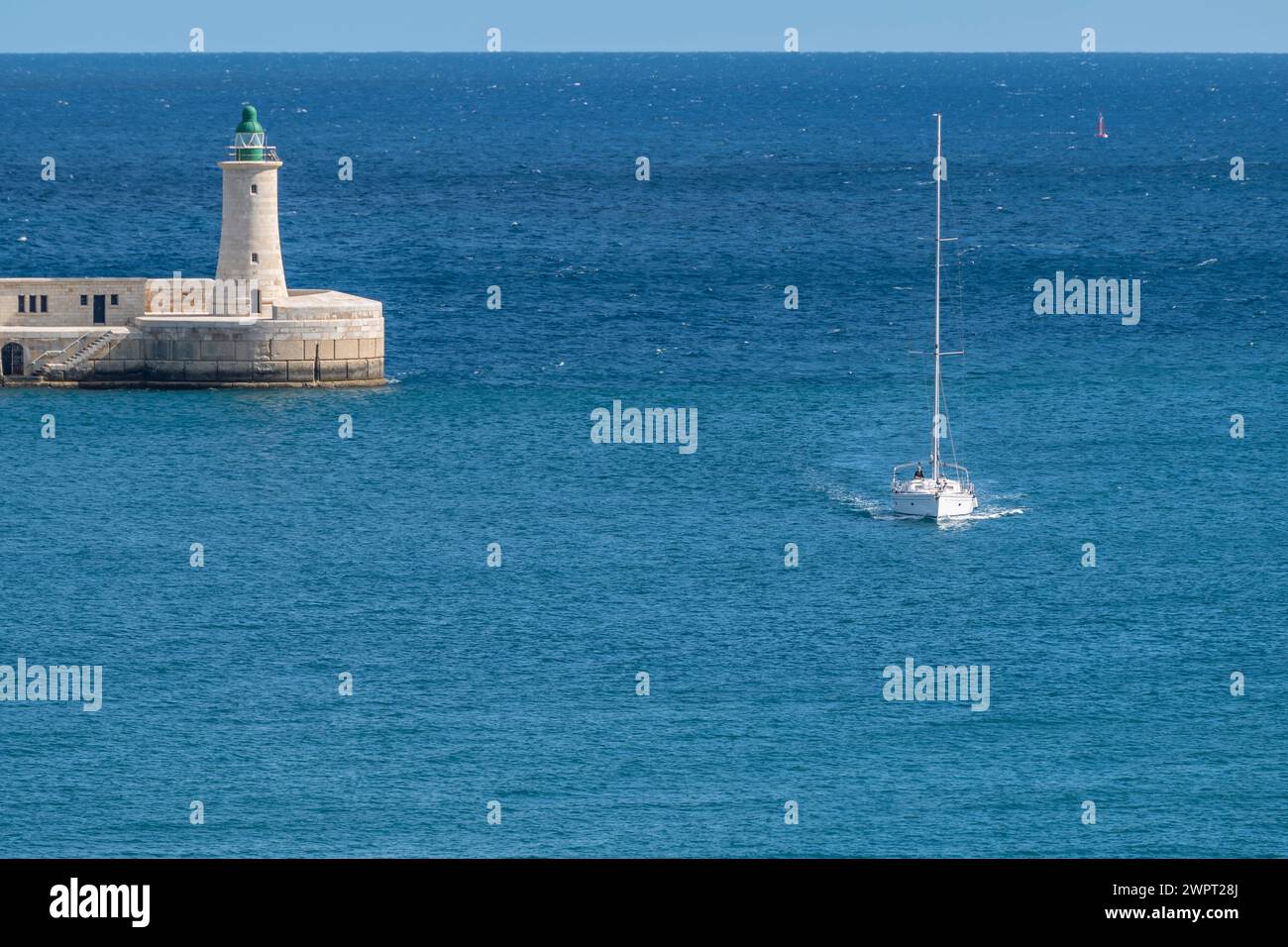 Una barca entra nel Grand Harbour di la Valletta con la St Faro frangiflutti Elmo sullo sfondo Foto Stock