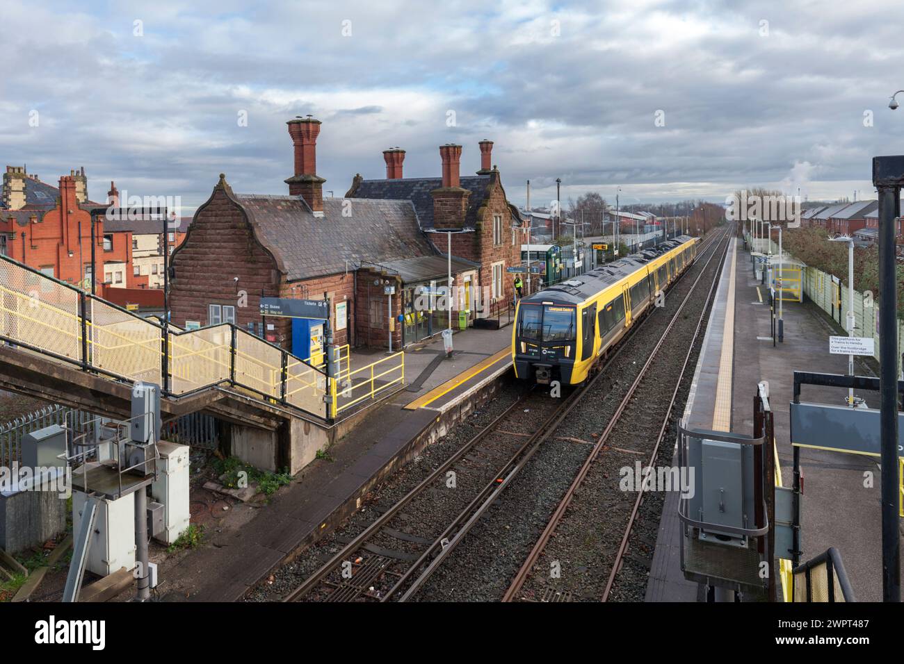 Treno elettrico Merseyrail Stadler classe 777 777006 presso la stazione ferroviaria di Ellesmere Port, Cheshire, Regno Unito con gli edifici della stazione Foto Stock