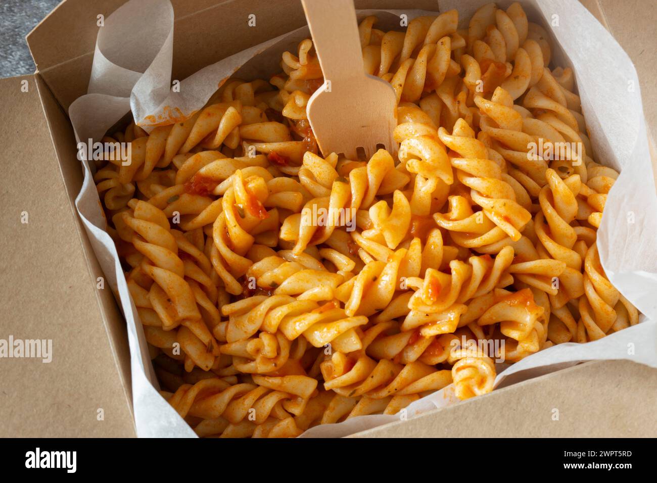 Fusilli in salsa di pomodoro ed erbe aromatiche da asporto in un contenitore di cartone. Contenitore da asporto ecologico e privo di plastica biodegradabile Foto Stock