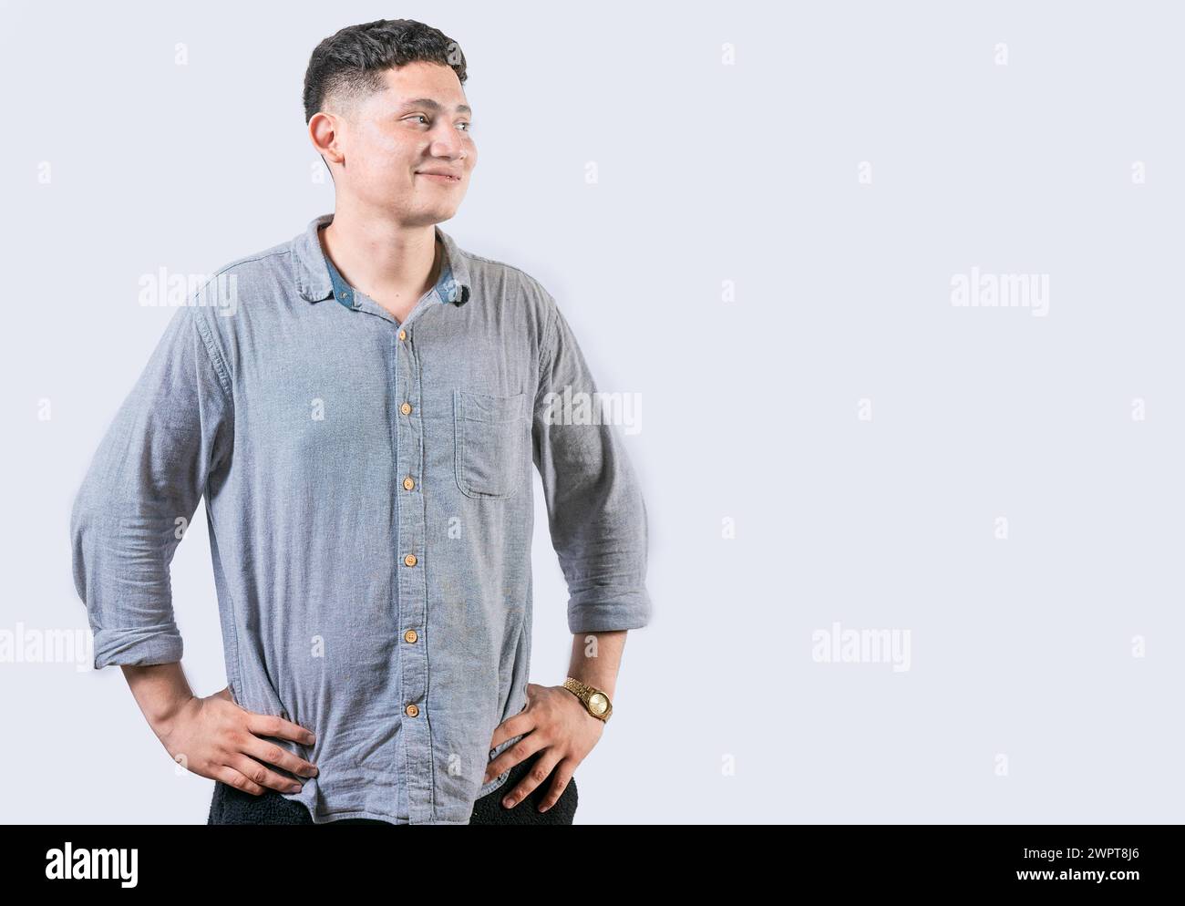 Giovane soddisfatto con le mani sull'anca che guarda da un lato. Giovane con le mani sui fianchi che guarda un annuncio a lato Foto Stock