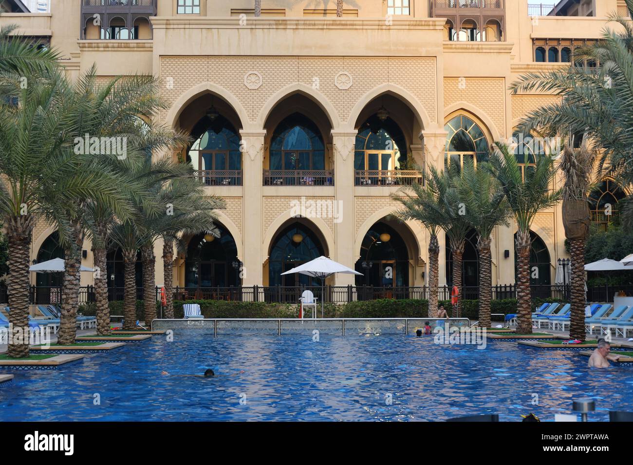Il tramonto cade sull'elegante facciata del Palace Downtown, annidato tra lussureggianti palme e una piscina riflettente. Dubai, Emirati Arabi Uniti - 15 agosto 2023 Foto Stock