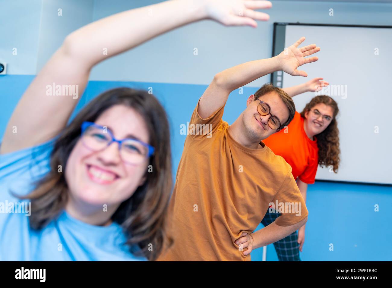 Concentrazione selettiva su un uomo con sindrome di Down e amici che frequentano lezioni di palestra Foto Stock