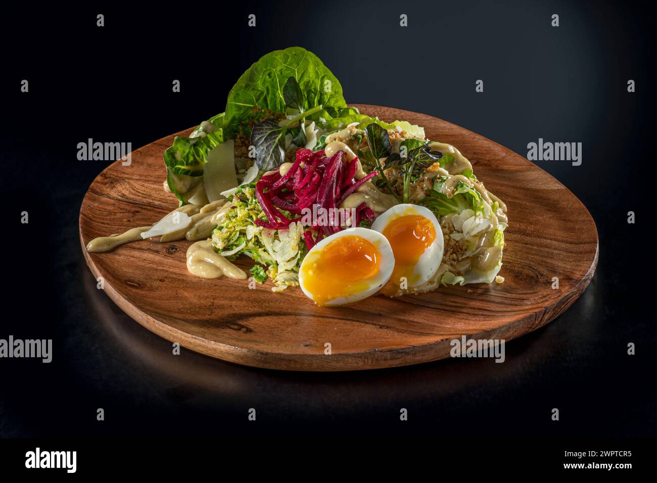 Insalata su piatto di legno con uova sode morbide Foto Stock
