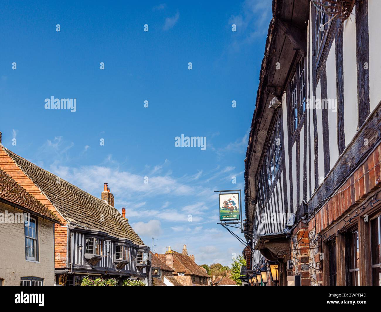 L'insegna bianca e nera del George Inn e pub in High Street, Alfriston, un grazioso villaggio storico nel quartiere Wealden dell'East Sussex Foto Stock