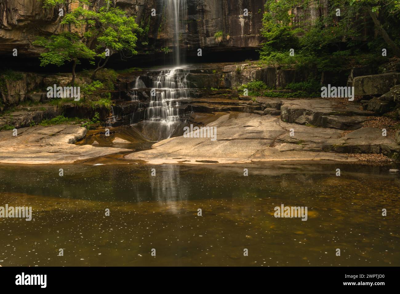 La tranquillità di una cascata in un ambiente boschivo poco illuminato con una superficie d'acqua riflettente, in Corea del Sud Foto Stock