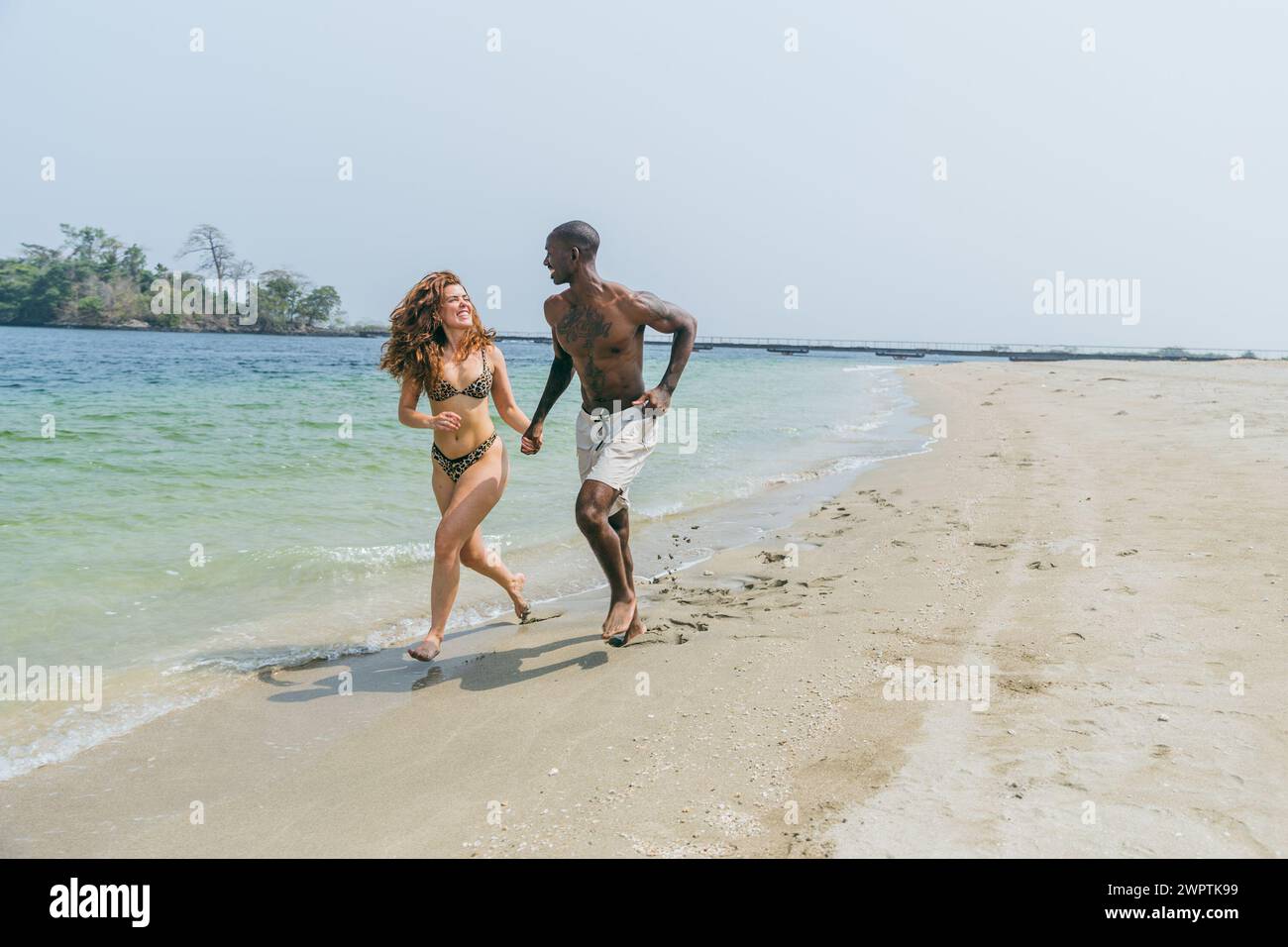 Una coppia corre sulla spiaggia e si diverte durante le vacanze al mare in Africa. Foto Stock