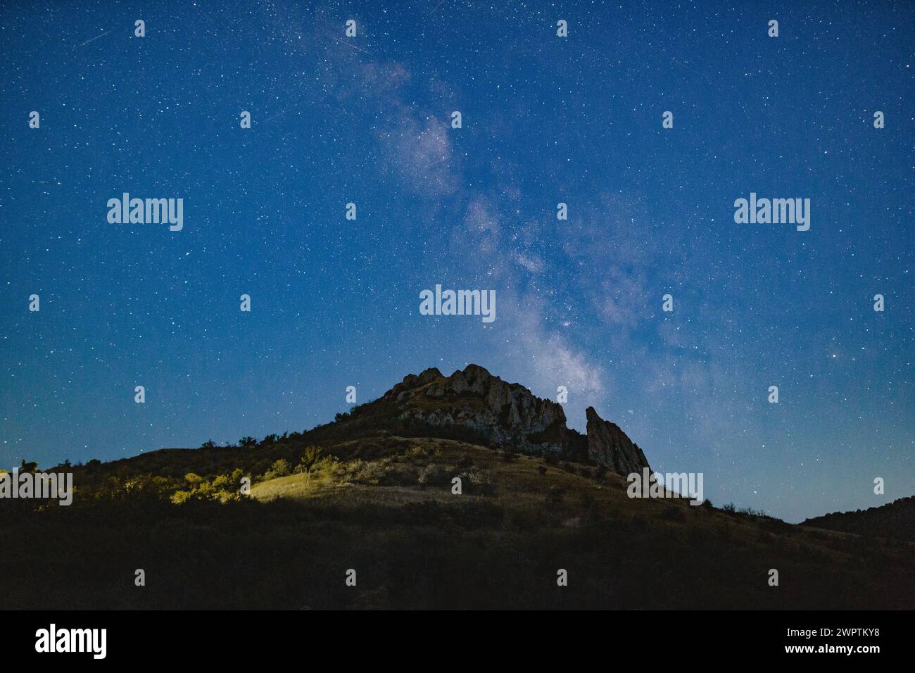 La Galassia della via Lattea in un cielo blu sopra una catena montuosa. Foto Stock