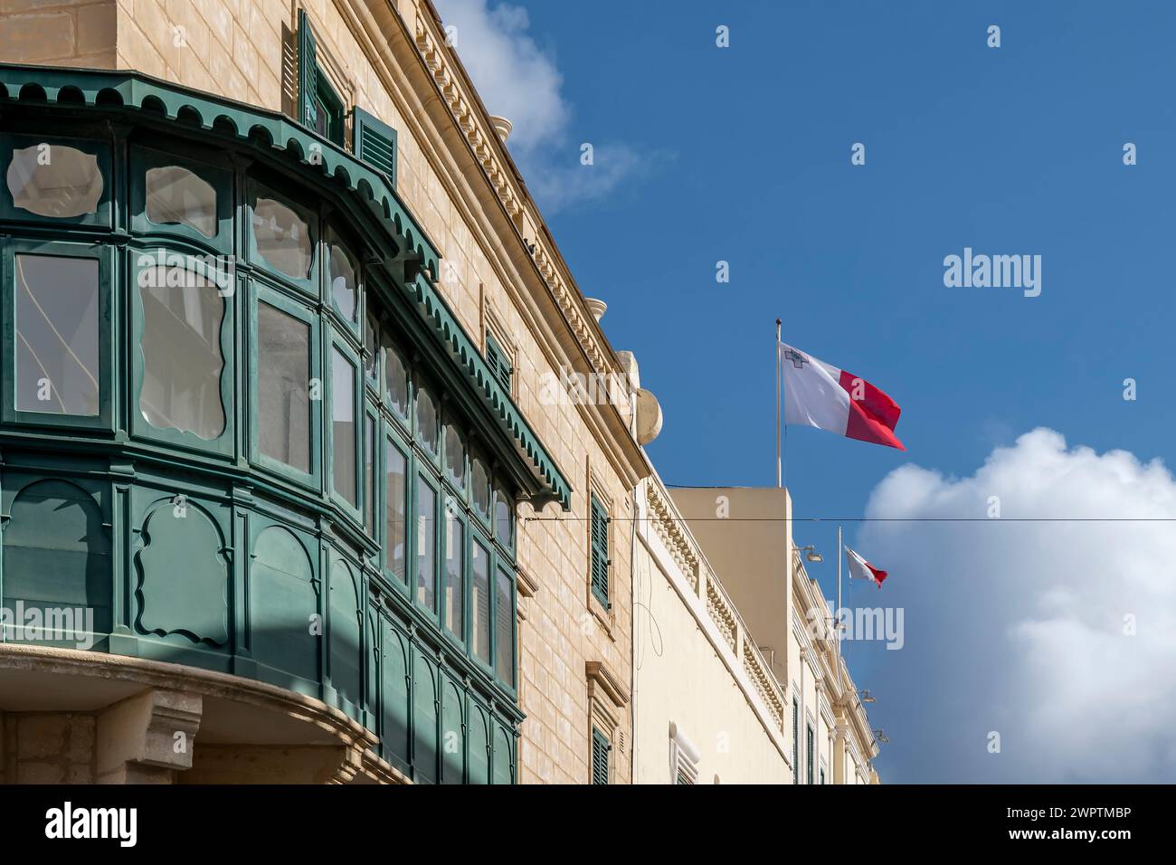 Una Gallarija verde, un elemento tipico dell'architettura vernacolare maltese, con bandiere maltesi che soffiano al vento, la Valletta, Malta Foto Stock