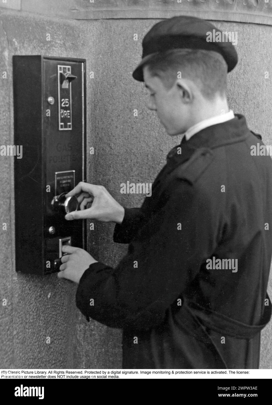 Negli anni '1930 Un uomo acquista dei gettoni da usare in casa sua quando aveva bisogno di usare il gas per alimentare il fornello o il riscaldatore della cucina. La moneta è stata immessa in un contatore in casa, iniziando una sequenza di gas limitata nel tempo. Al termine del tempo, il gas si è fermato. 1935. Foto Stock