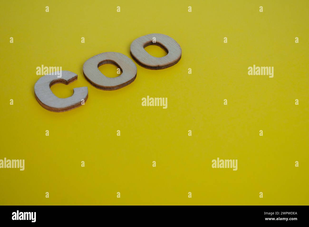 Lettere di legno COO su sfondo giallo della copertina. Concetto di livello Senior Executive. Foto Stock