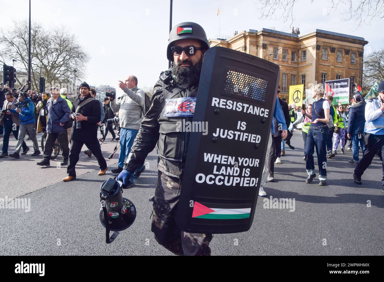 Londra, Regno Unito. 9 marzo 2024. Un manifestante che indossa un'uniforme da stampa in tempo di guerra tiene uno scudo con slogan filo-palestinesi durante la manifestazione. Migliaia di persone marciano verso l'ambasciata degli Stati Uniti in solidarietà con la Palestina, chiedendo un cessate il fuoco mentre la guerra Israele-Hamas continua. Credito: SOPA Images Limited/Alamy Live News Foto Stock