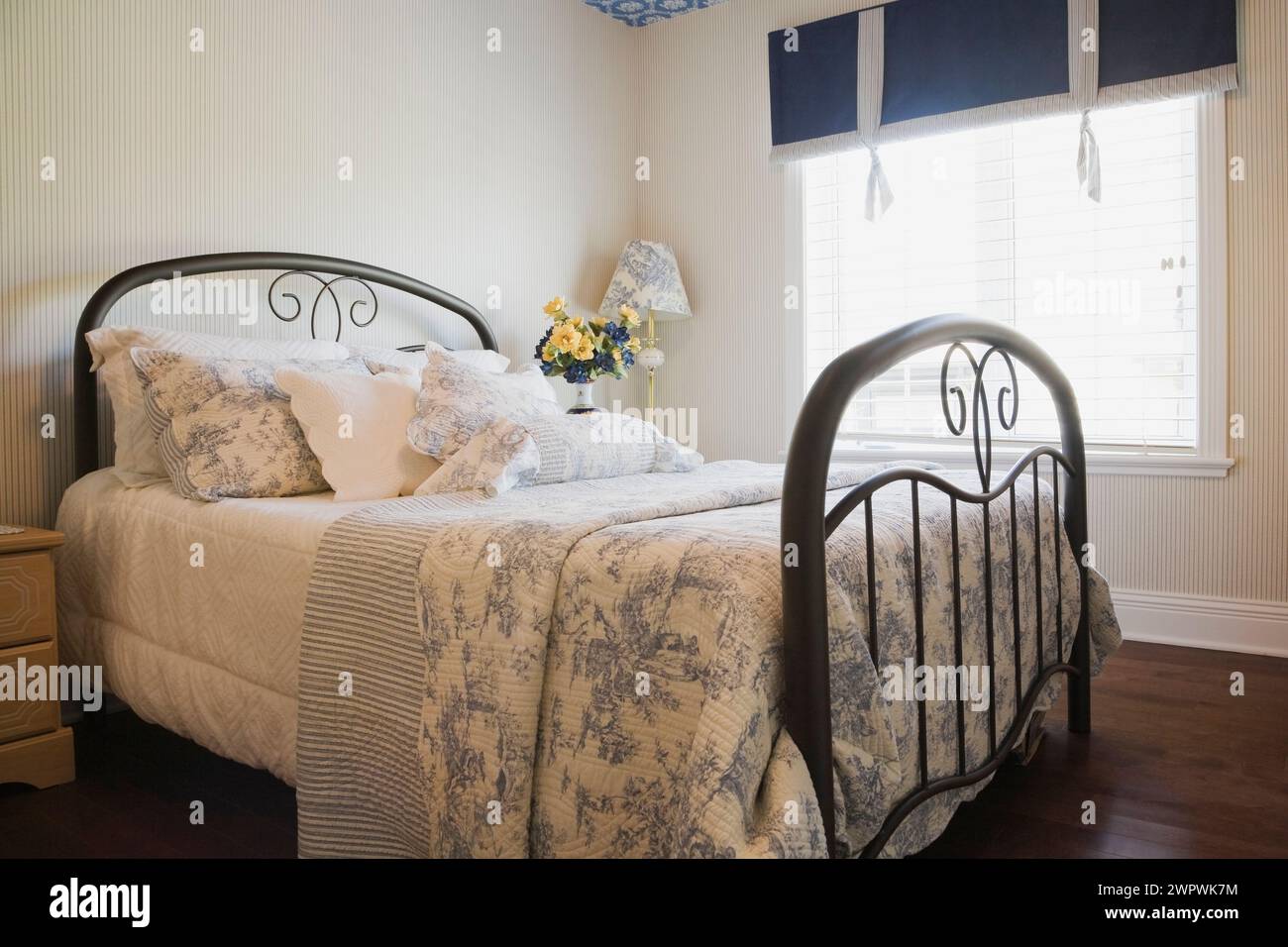 Letto antico con testiera e pediera in metallo tubolare, con motivi floreali blu, copriletto in camera da letto all'interno sontuosamente decorata e lussuosa casa. Foto Stock