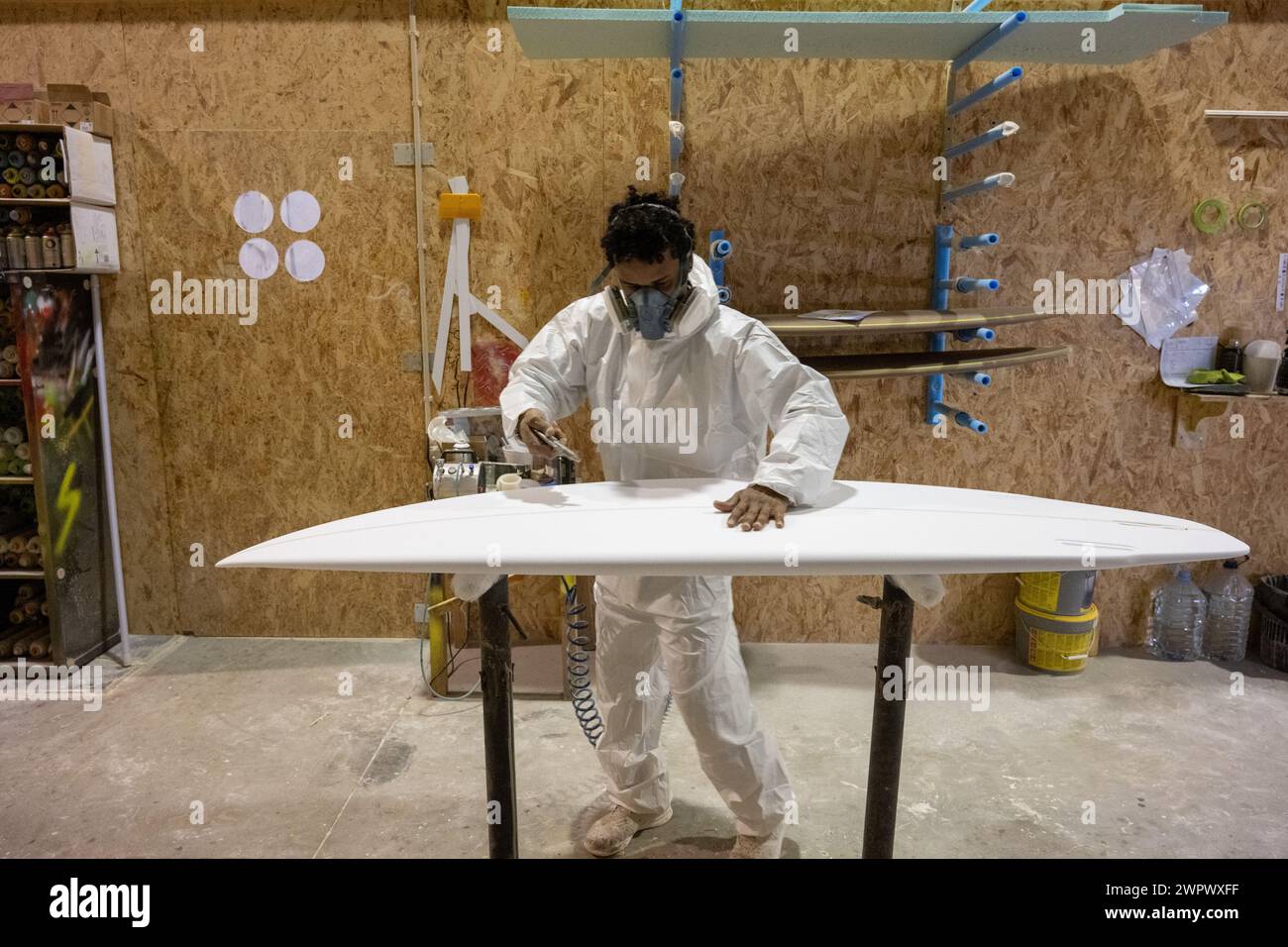 Produzione di tavole da surf, Shaper che lavora sui dettagli della tavola. Concetto di produzione industriale, professionale qualificata, professione e occupazione. Foto Stock