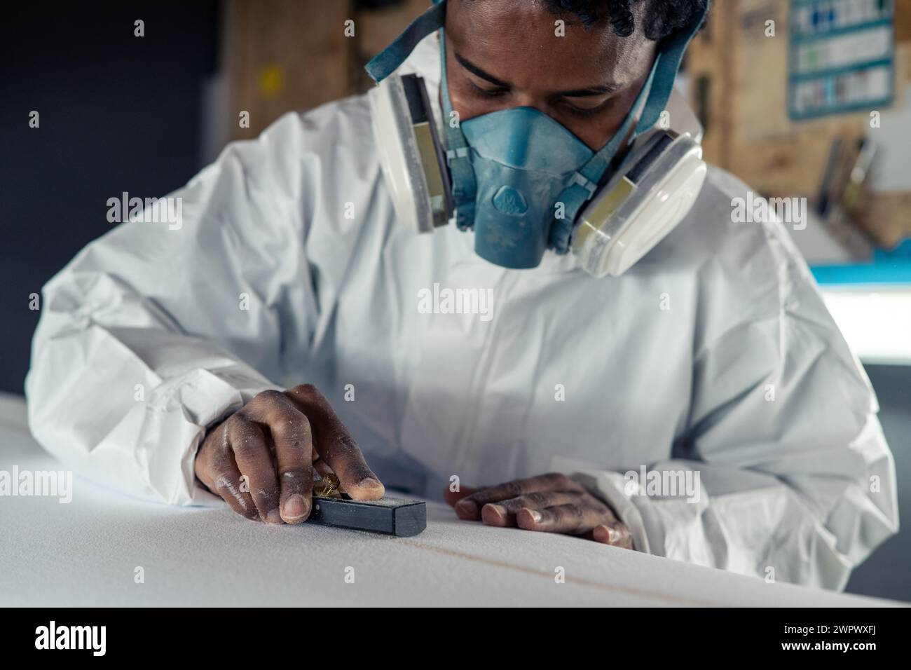 Produzione di tavole da surf, Shaper che lavora sui dettagli della tavola. Concetto di produzione industriale, professionale qualificata, professione e occupazione. Foto Stock