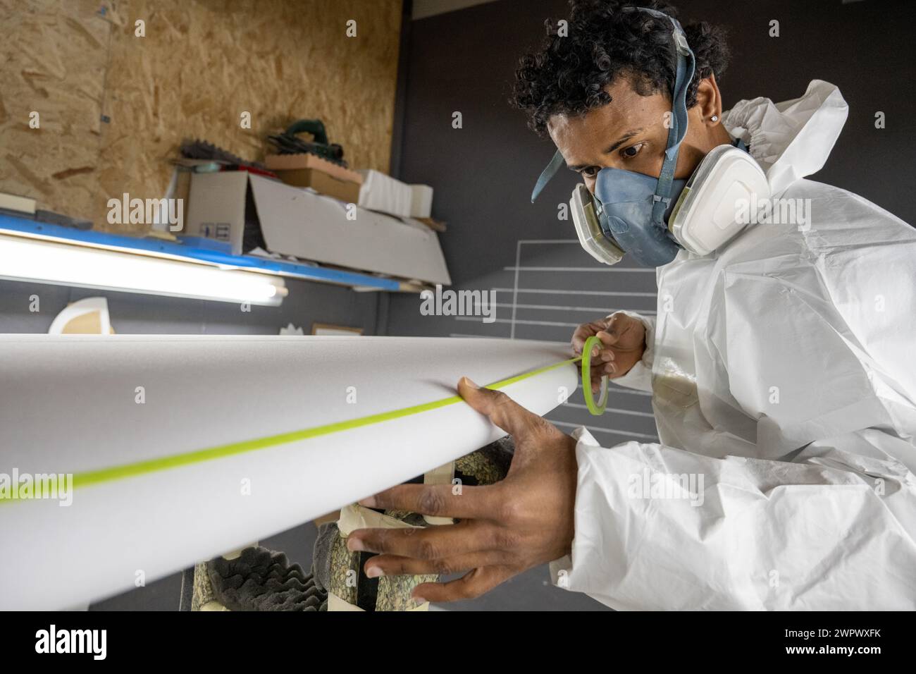 Produzione di tavole da surf, Shaper che lavora sui dettagli della tavola. Concetto di produzione industriale, professionale qualificata, professione e occupazione. Foto Stock