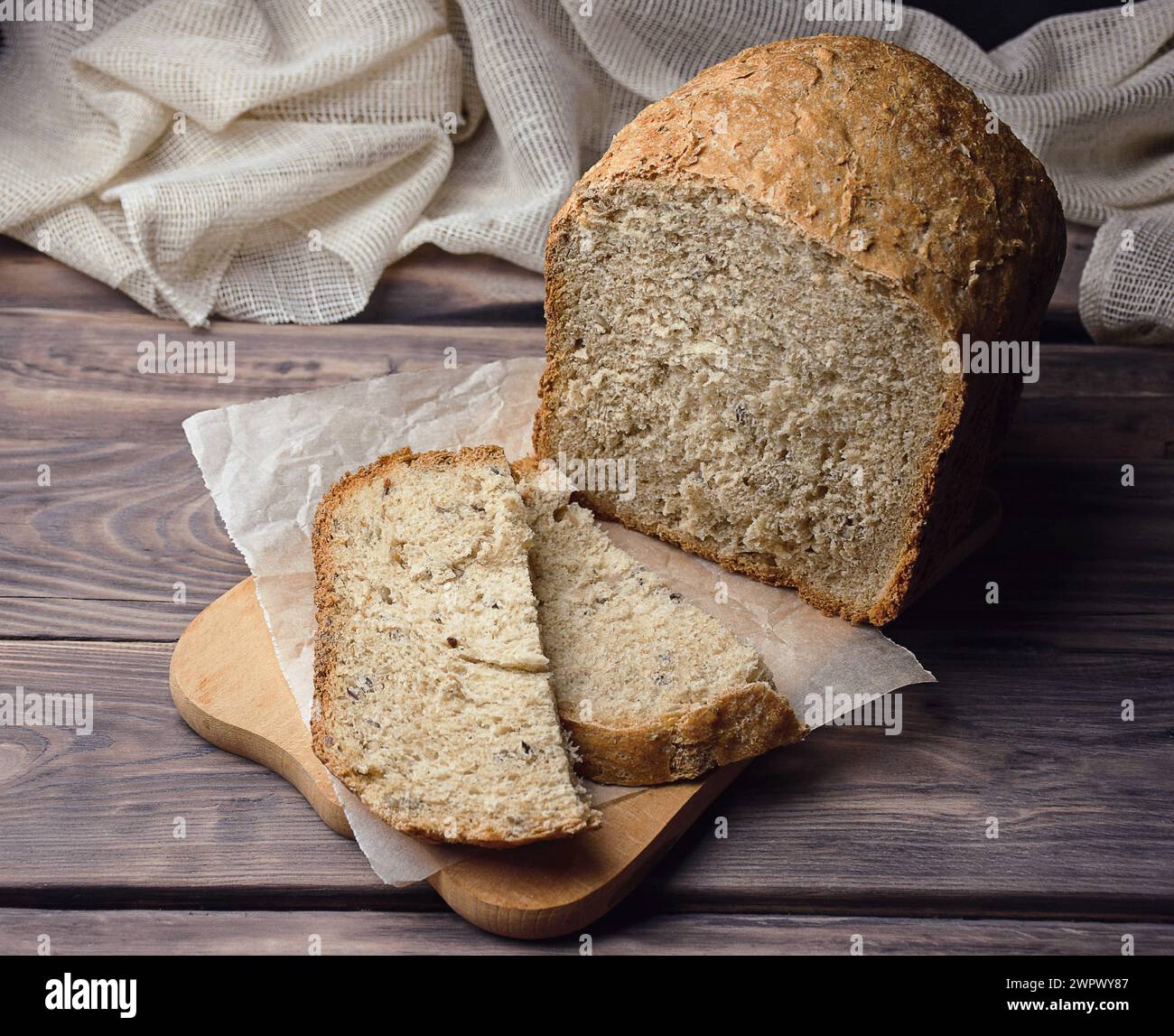 Pane di grano integrale fresco fatto in casa. Consistenza del pane. Pane tradizionale a lievitazione naturale tagliato a fette su uno sfondo rustico in legno. Concetto di tradizione Foto Stock