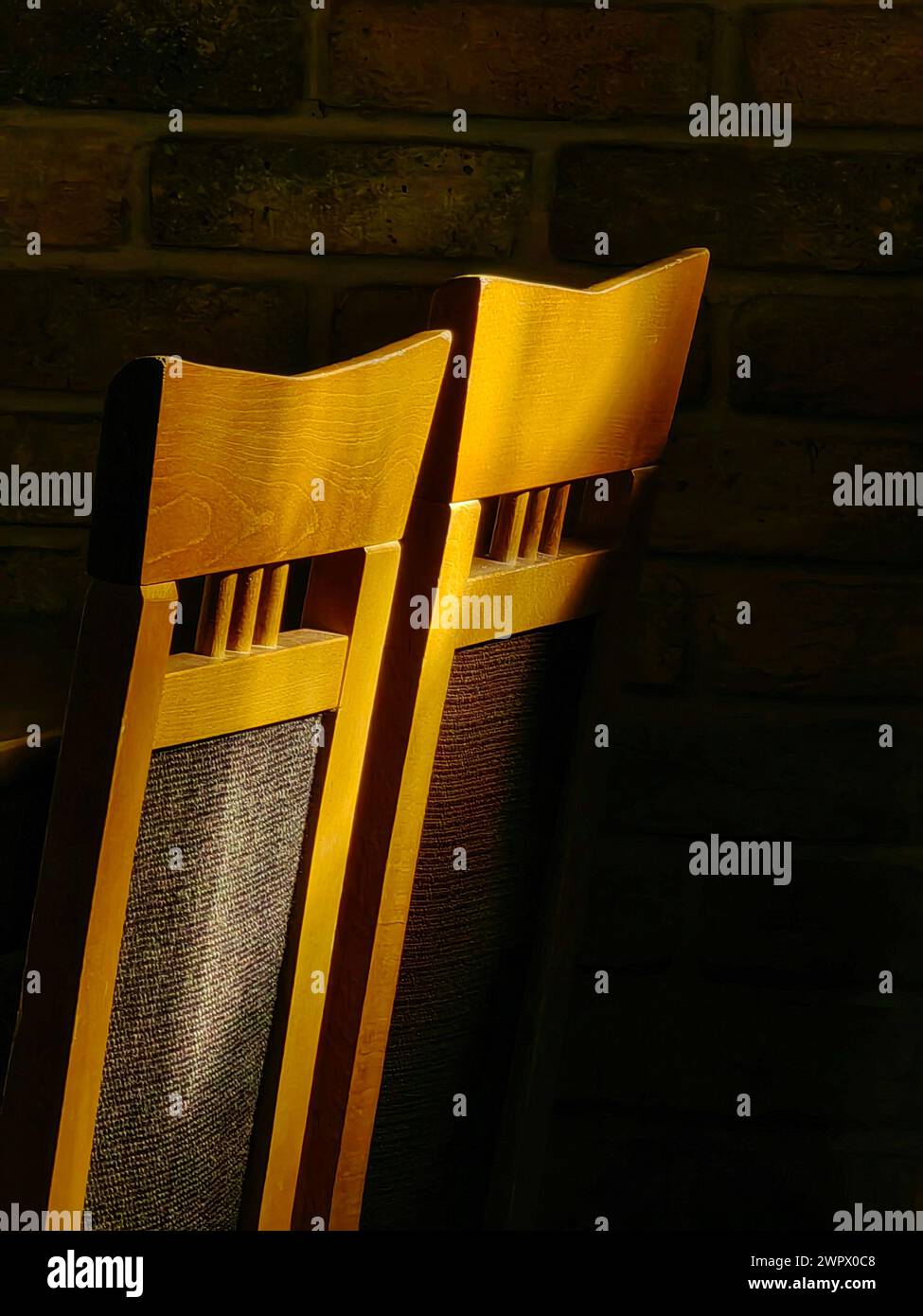 Posti a sedere illuminati dal sole. Illuminare due sedie marrone chiaro in uno spazio buio. Foto Stock