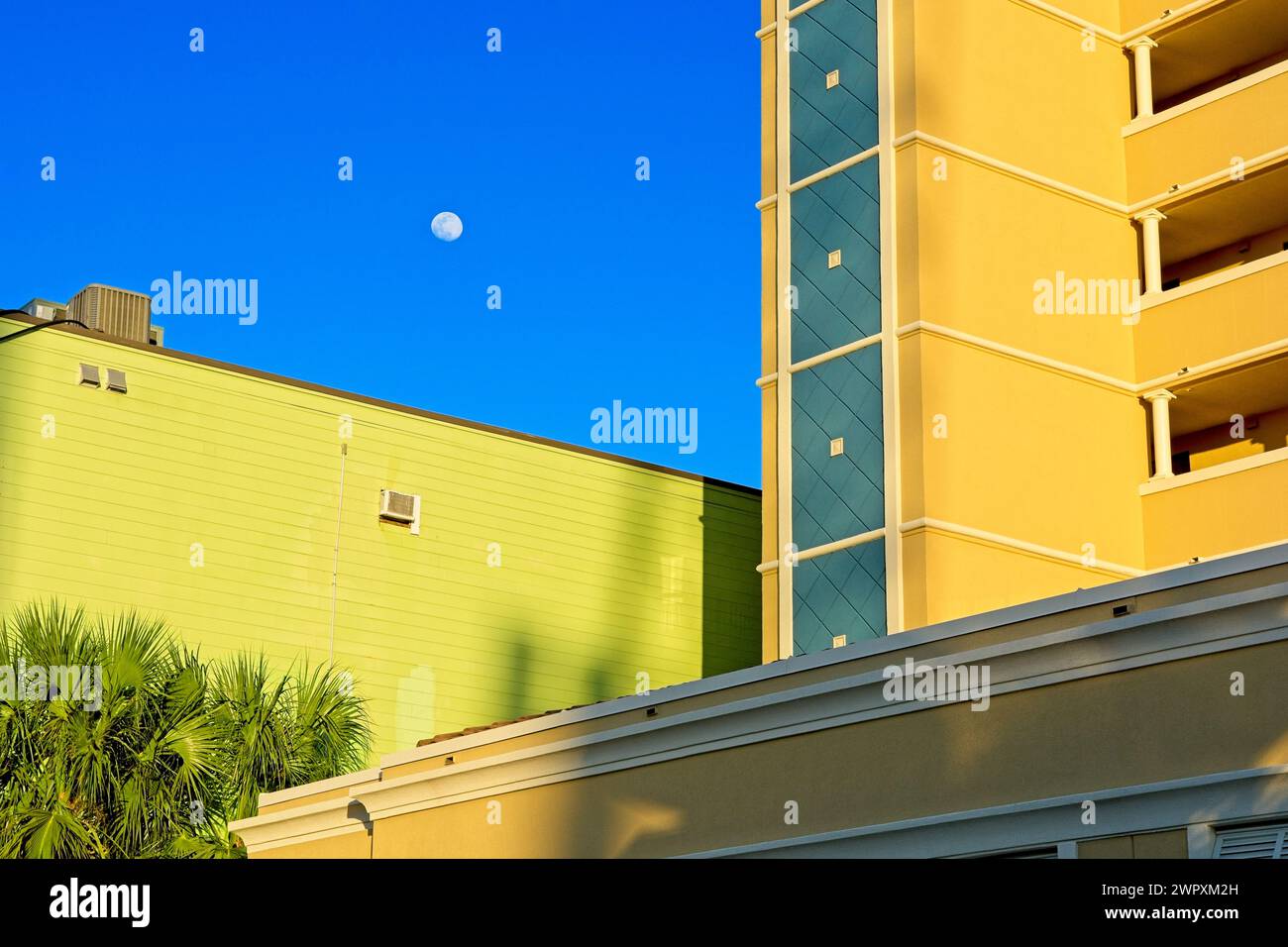 Luna nel cielo blu sopra edifici residenziali luminosi Foto Stock